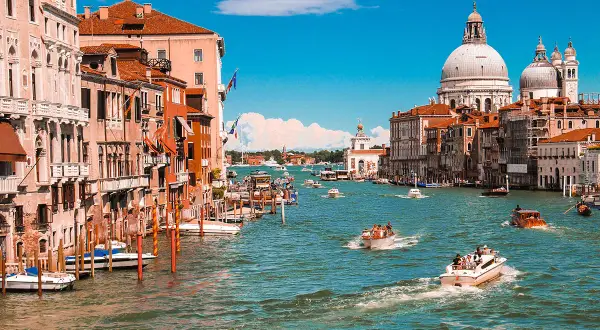 Venedig, ein Traumziel für jeden Kurztrip in Europa. Boote gleiten über das türkisfarbene Wasser, vorbei an prächtigen Palästen und der imposanten Basilika Santa Maria della Salute.
