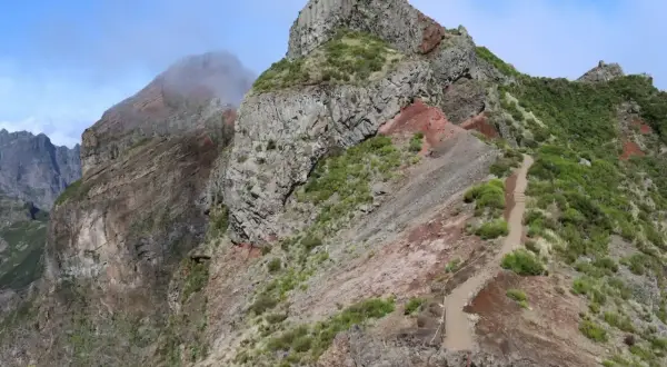 Steiler Wanderweg auf Madeira, ideal für die Packliste. Felsen und grüne Vegetation prägen die Landschaft.