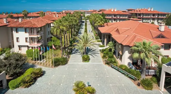 Blick auf das Club Grand Side Resort mit Palmen und roten Ziegeldächern.