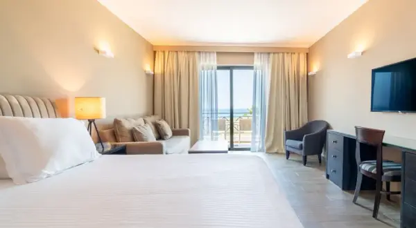Gemütliches Zimmer im sentido pelagos suites & spa mit Meerblick vom Balkon. Einladendes Bett, Sofa und Schreibtisch.
