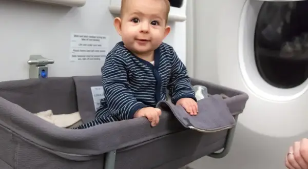 Kleines Baby in Flugzeug-Babywiege, der beste Sitzplatz im Flugzeug mit Kleinkind für eine entspannte Reise.