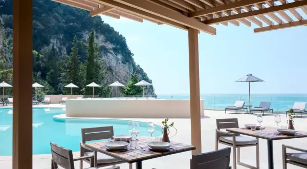 Ein gedeckter Tisch am Pool mit Blick aufs Meer. Der alkyna lifestyle beach resort bietet pure Entspannung.