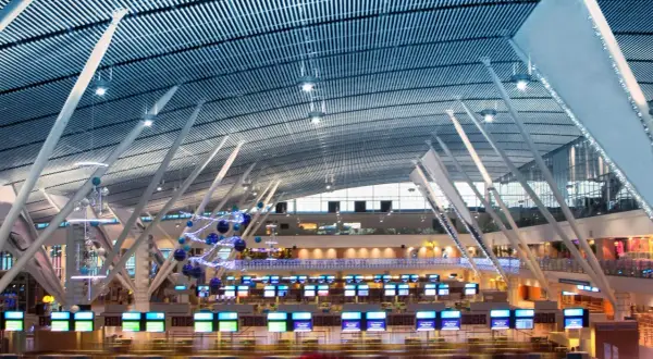 Moderne Flughafenhalle mit vielen Check-in-Schaltern, die für das standby fliegen bereit sind. Die geschwungene Decke und die stützenartige Architektur sind beeindruckend.