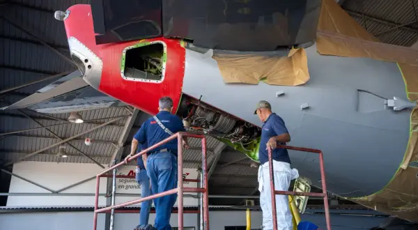 Zwei Mechaniker auf einer Hebebühne arbeiten am Triebwerk eines Flugzeugs. Ein wichtiger Begriff aus der Fliegerei wird hier greifbar.
