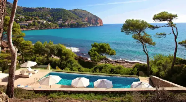 Traumhafter Poolblick auf das Meer bei Simoneta Mallorca. Sonnenschirme und Liegen laden zum Entspannen ein.