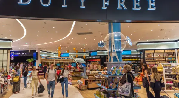 Menschen bummeln durch einen beleuchteten duty free Shop mit vielen Waren.