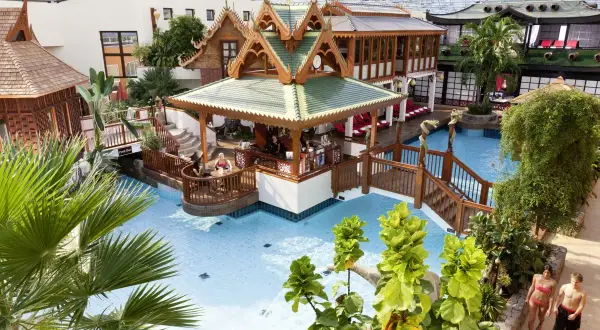 Tropisches Paradies im Sieben Welten Hotel & Spa Resort: Poollandschaft mit asiatischem Flair, Bar und Palmen.