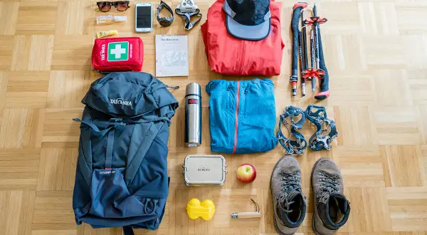 Packliste Bergtour: Rucksack, Wanderschuhe, Steigeisen, Jacken, Mütze, Wanderstöcke, Erste-Hilfe-Set, Thermoskanne, Handy, Sonnenbrille, Karte.