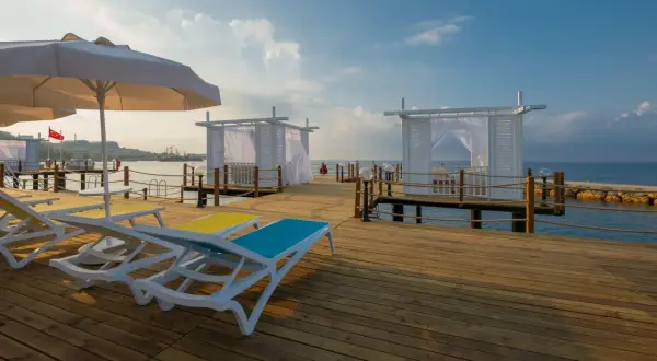 Sonnenliegen und weiße Pavillons auf einem Holzsteg am Meer, ein perfekter Ort für einen Urlaub im Mary Hotel Alanya.