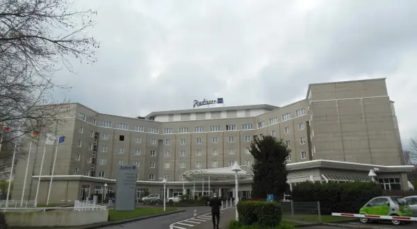 Das Radisson Blu Hotel Dortmund, ein imposantes Gebäude mit vielen Fenstern, empfängt seine Gäste unter einem grauen Himmel.