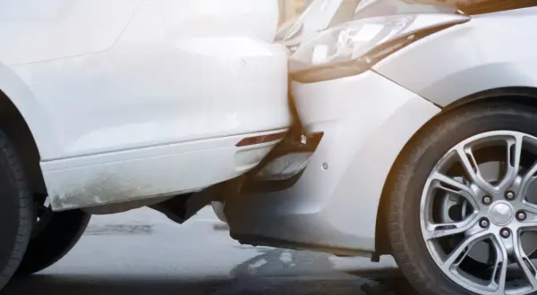 Zwei Autos sind kollidiert, ein weißes und ein silbernes. Der Unfall beim Ausparken hat die Stoßstangen und Scheinwerfer beschädigt.