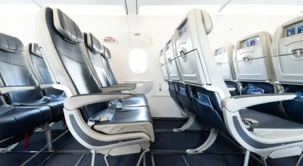 Leere Sitze in einem Flugzeug von Freebird Airlines. Blaue und graue Polster, Bildschirme an den Rückenlehnen.