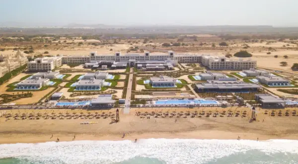 Luftaufnahme des Riu Palace Boavista Hotels mit mehreren Gebäuden, Pools und einem Strand mit Sonnenschirmen.