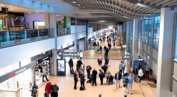 Menschen im Hamburger Flughafen, einige eilen zu ihren Gates, andere suchen nach Möglichkeiten, Geld zu wechseln.