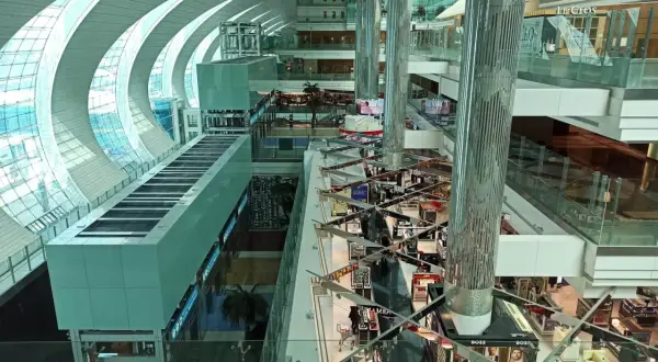 Der Flughafen Dubai innen: ein modernes Einkaufsparadies mit Glas und Stahl. Helle Gänge, Geschäfte und Palmen laden zum Verweilen ein.
