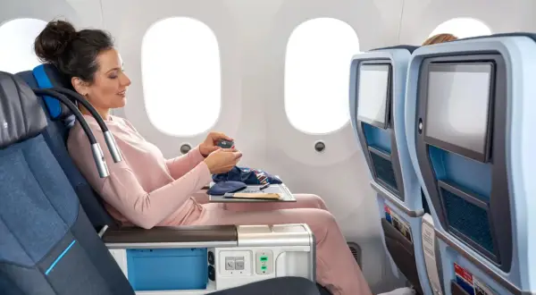 Frau im KLM Flugzeug entspannt sich mit einem kleinen Beutel.