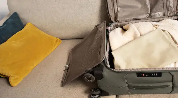 Koffer packen für den Urlaub. Kleidung wird sorgfältig in den Koffer gelegt, bereit für die Reise.