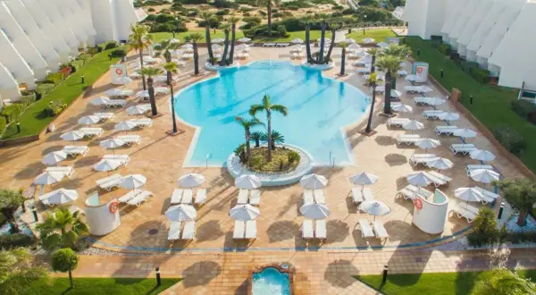 Traumhafter Poolbereich mit Liegen und Sonnenschirmen am IBEROSTAR Royal Andalus. Der Strand und das Meer sind im Hintergrund zu sehen.