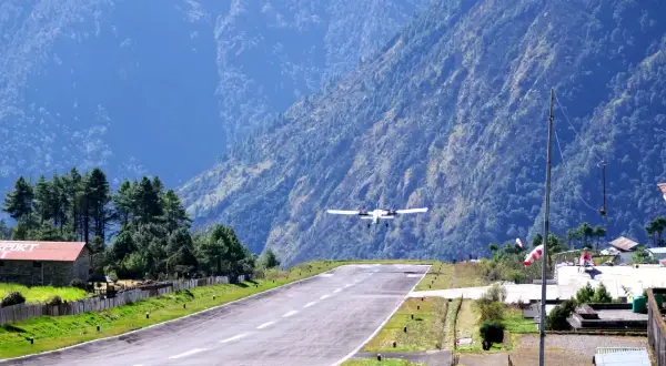 Flugzeug landet auf dem Lukla Airport, umgeben von steilen, bewaldeten Bergen.