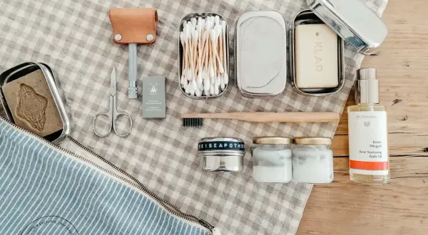 Kosmetik urlaub liste: Rasierer, Seife, Wattestäbchen, Zahnbürste, Cremetiegel und Rosenöl für die Reiseapotheke.