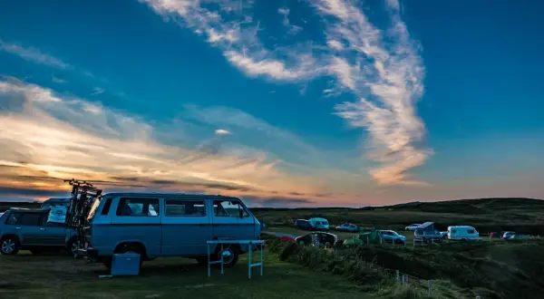 Sonnenuntergang auf einem Campingplatz mit vielen Fahrzeugen, die sich den Platz teilen.