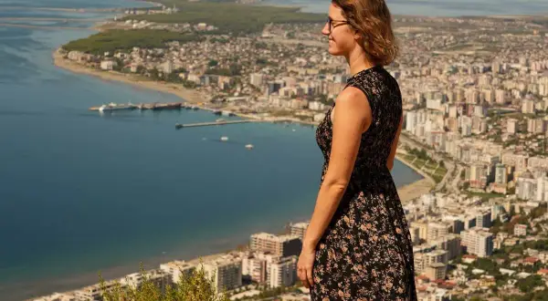 Frau genießt den Ausblick auf eine Stadt am Meer während ihres Urlaubs in Albanien.