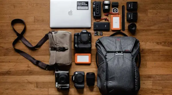 Perfekte work and travel packliste: Laptop, Kameras, Objektive, Speicherkarten, externe Festplatten, Blitzgeräte und ein Rucksack.