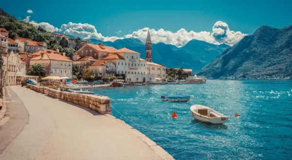 Traumhafte Küstenstadt mit roten Dächern und Booten im türkisfarbenen Wasser. Ein perfektes Beispiel für Urlaubsziele in Europa.