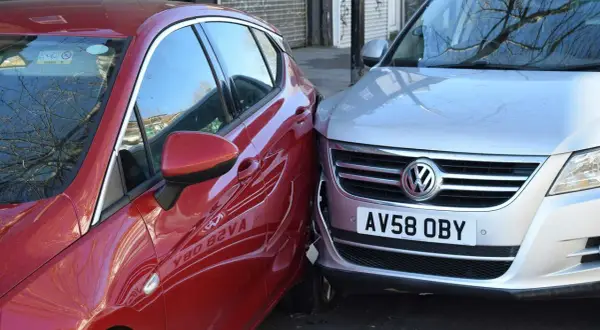 Mein parkendes Auto wurde angefahren. Ein rotes Auto ist seitlich gegen einen silbernen VW gestoßen.