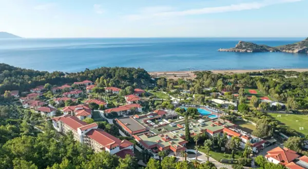 Luftaufnahme des TUI Blue Sarigerme Park mit Blick auf das Meer, Pools und Tennisplätze, eingebettet in üppige grüne Bäume.