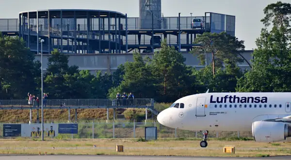 Lufthansa Airbus A320-200 auf dem Rollfeld in Frankfurt. Im Hintergrund ein Parkhaus und Bäume.