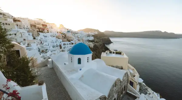 Ein malerischer Blick auf Oia, Santorini, mit seinen weiß getünchten Häusern und der ikonischen blauen Kuppelkirche. Perfekt für einen Santorini Urlaub.