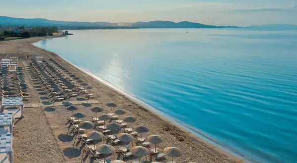 Ein traumhafter Strand mit vielen Liegen und Sonnenschirmen, bereit für Gäste des TUI Blue Lagoon Princess. Das Meer glitzert in der Sonne.