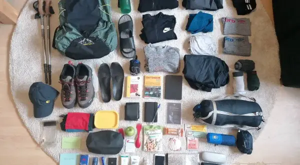Jakobsweg Packliste: Rucksack, Wanderschuhe, Kleidung, Trinkflasche, Wanderstöcke, Hygieneartikel und Verpflegung für eine Pilgerreise.