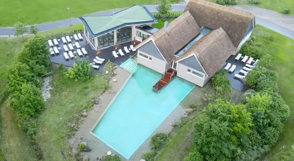 Beech Resort Plauer See: Einladender Poolbereich mit Liegen und moderner Architektur, umgeben von Grün.