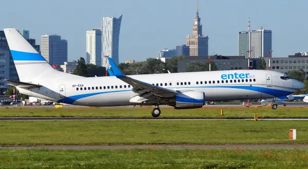 Ein Enter Air Flugzeug rollt auf dem Rollfeld, die Skyline von Warschau im Hintergrund.