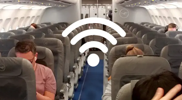 WLAN im Flugzeug: Passagiere sitzen in Reihen auf Flugzeugsitzen, während ein großes WLAN-Symbol über ihnen schwebt.