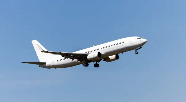 Ein weißes Flugzeug steigt in den blauen Himmel auf. Die Frage, wie hoch fliegt ein Flugzeug, bleibt offen, aber dieser Anblick lässt die Fantasie fliegen.