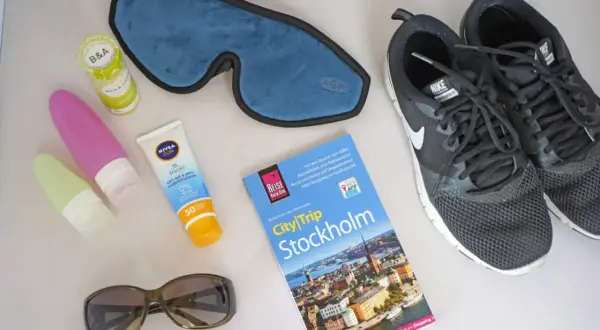 Packliste Wochenende: Sonnencreme, Schlafmaske, Sonnenbrille, Reiseführer Stockholm und Turnschuhe für Stadterkundungen.