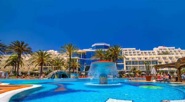 Einladender Poolbereich mit Wasserrutsche und Palmen vor dem Costa Calma Palace Hotel.