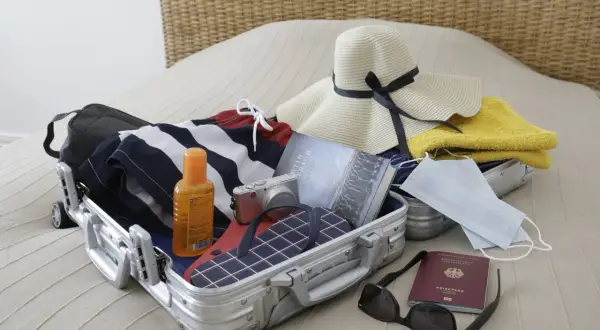 Packliste Istanbul: Koffer mit Badesachen, Sonnencreme, Kamera, Hut, Buch, Masken, Reisepass und Sonnenbrille.