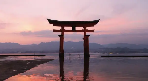 Ein rotes Torii-Tor im Wasser bei Sonnenuntergang. Ein unvergesslicher Moment auf einem Japan Urlaub.