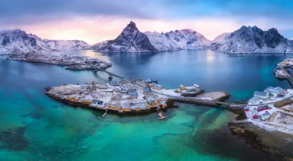 Winterliche Lofoten: Ein Traum für jeden Skandinavien Urlaub. Schneebedeckte Berge, türkisfarbenes Wasser und malerische Fischerdörfer.