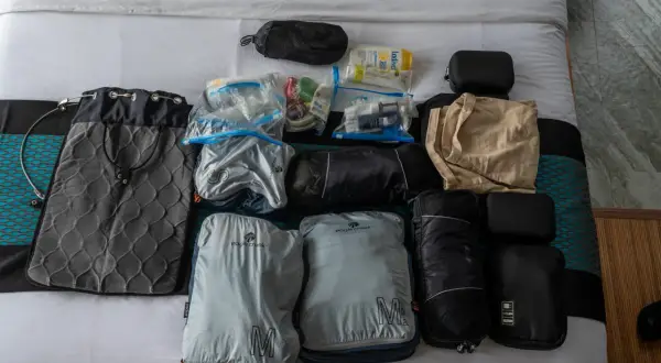 Packliste Thailand: Gepäckstücke, Kulturbeutel und Kleidung sind ordentlich auf dem Bett ausgebreitet.