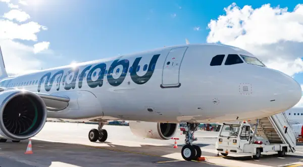 Ein weißes Flugzeug der Marabu Airlines steht am Flughafen. Die Sonne scheint auf den Rumpf, und eine Treppe ist am Eingang angebracht.