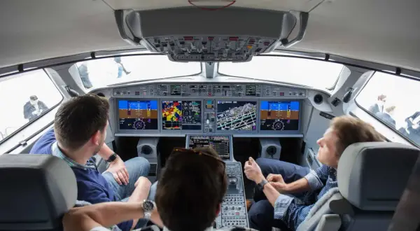 Einblick ins Cockpit: Drei Männer blicken auf die Instrumente, während sie im Flugzeug mitfliegen.