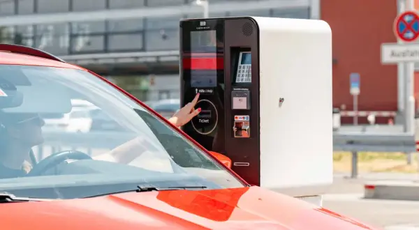 Frau am Parkscheinautomaten am Flughafen Memmingen. Hier kann man kostenlos parken, wenn man den richtigen Tarif wählt.