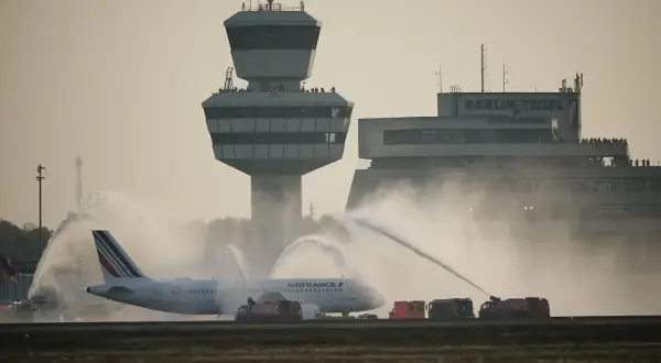 Air France Flugzeug wird auf dem Rollfeld der Berlin Airports mit Wasser begrüßt. Der Kontrollturm und das Terminal sind im Hintergrund zu sehen.