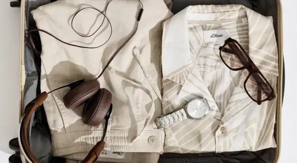 Koffer packen Liste Frauen: Leinenhose, gemustertes Hemd, Kopfhörer, Brille und Uhr für den perfekten Urlaub.