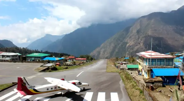 Ein kleines Flugzeug steht auf dem Rollfeld des Nepal Flughafens, umgeben von majestätischen Bergen.